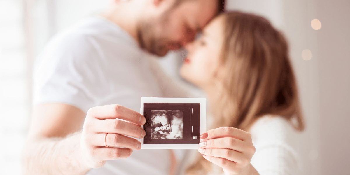 Un couple amoureux de futurs parents montre une photo d'une échographie