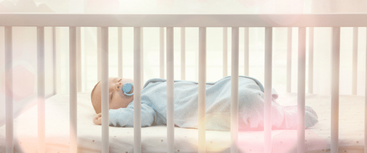 un bébé dort dans son petit lit à barreau sur son matelas bio